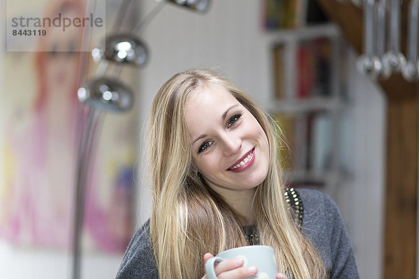 Porträt einer lächelnden jungen Frau mit Teetasse