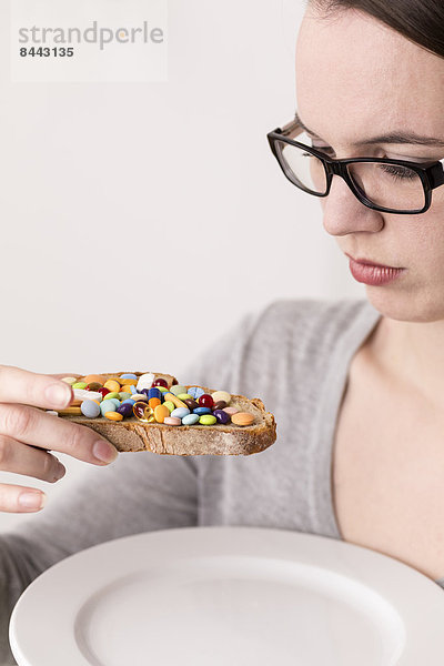 Junge Frau hält Brot  garniert mit vielen Tabletten