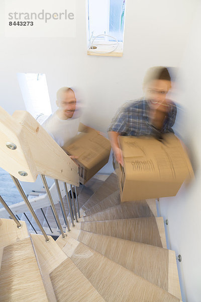 Young couple moving into new home  carrying cardboard boxes