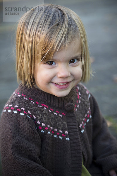 Porträt eines lächelnden kleinen Mädchens mit Strickjacke