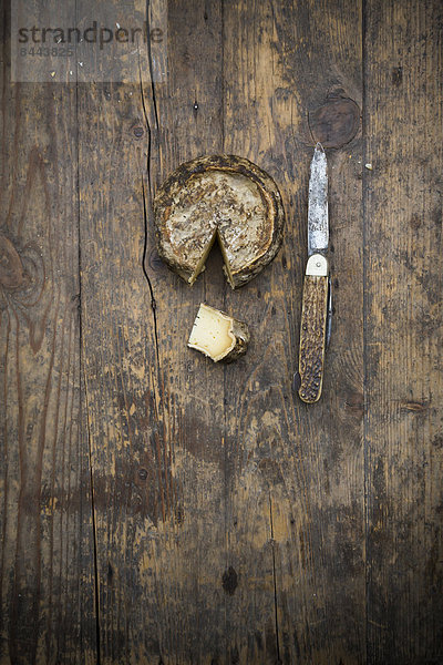 Tomme de Savoie Käse und Messer auf Holztisch