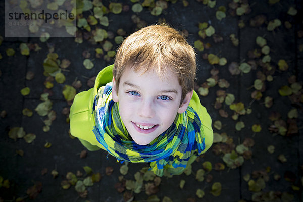 Elevated view of smiling young boy with hoodie jacket and scarf