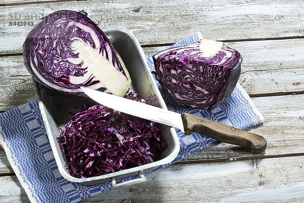 Red cabbage  kitchen knife and kitchen towel on wooden table