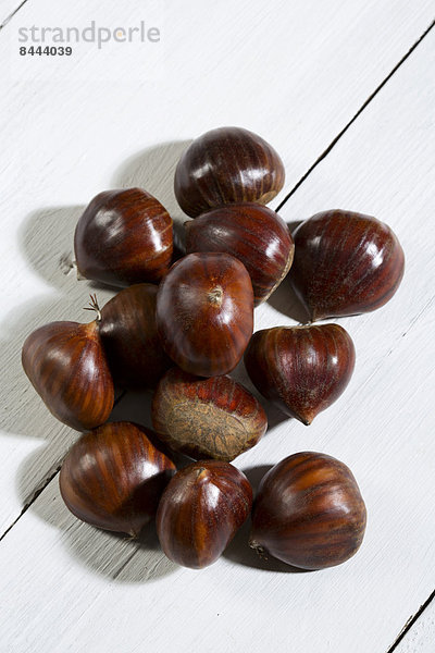 Spanish chestnuts (Castanea sativa) on white wooden table
