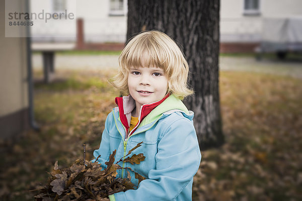 Porträt eines kleinen Jungen mit Herbstblättern
