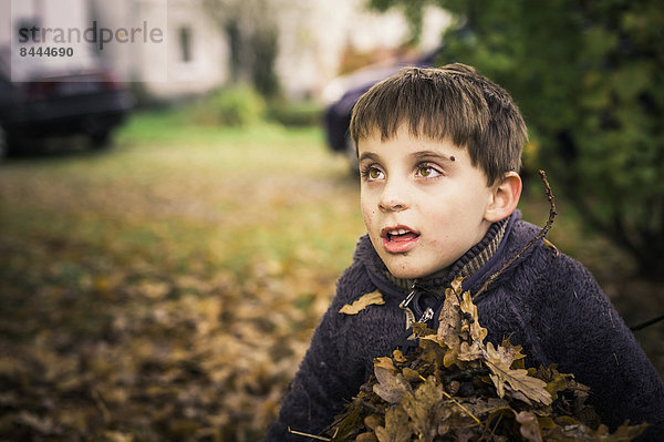 Kleiner Junge mit Herbstlaub im Arm