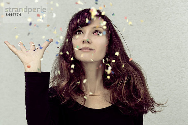 Young woman looking at confetti in the air