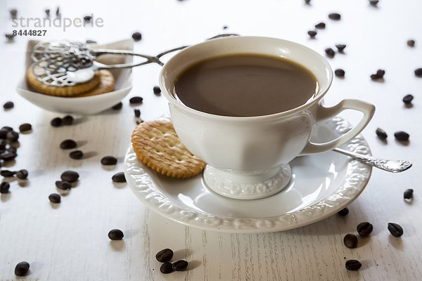 Tasse Kaffee  Kekse und verstreute Kaffeebohnen auf Holztisch
