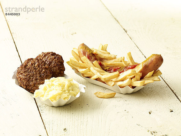 Curry sausage with French fries  two meatballs and mashed potatoes on wooden table