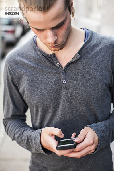 Junger Mann mit Handy im Freien