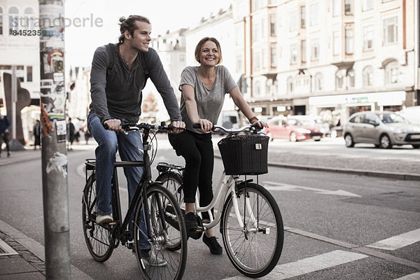 Ein glückliches Paar fährt mit dem Fahrrad durch die Stadt.