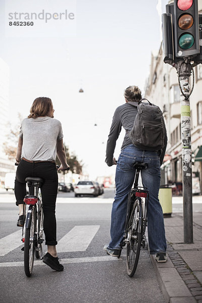 Rückansicht des Paares mit auf Signale wartenden Fahrrädern an der Stadtstraße