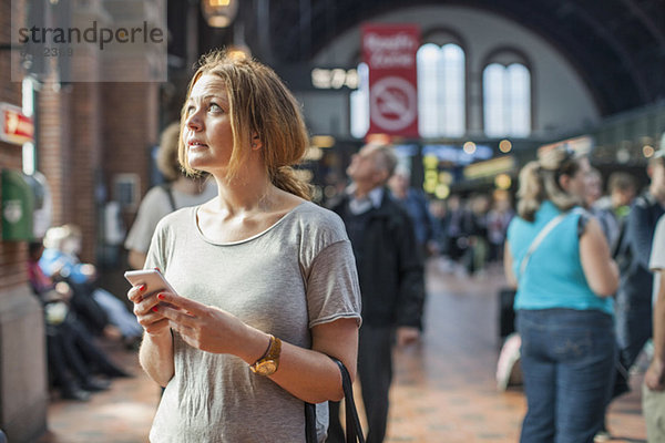 Mittlere erwachsene Frau mit Handy im Stehen auf dem Bahnhof