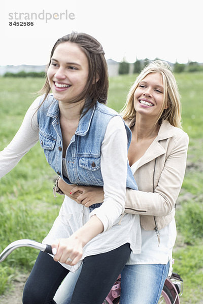 Fröhliche Freundinnen beim Radfahren auf der Landstraße