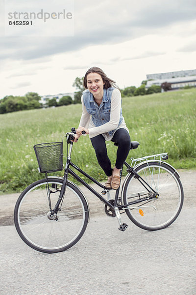Porträt einer glücklichen jungen Frau auf dem Fahrrad auf dem Land
