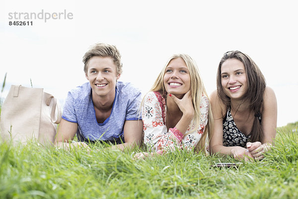 Nachdenkliche junge Freunde schauen weg  während sie auf dem Feld liegen.