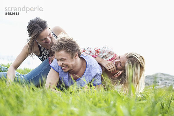 Verspielte junge Freunde stapeln sich auf dem Feld.