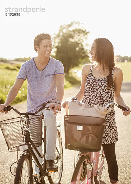 Glückliches junges Paar mit Fahrrädern auf dem Landweg