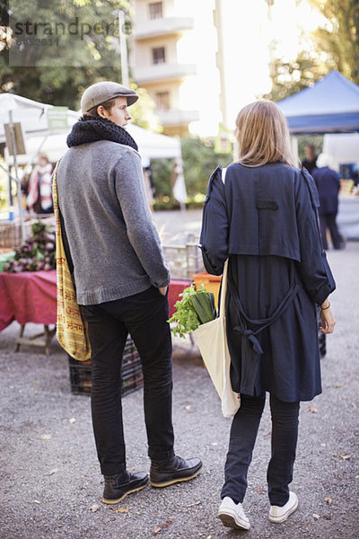 Rückansicht des jungen Paares mit Blattgemüse auf dem Markt