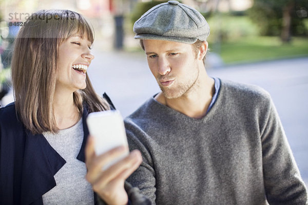 Ein glückliches Paar fotografiert sich selbst mit dem Handy im Freien.
