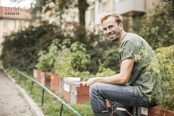 Seitenansicht Porträt eines glücklichen Mannes mit Schaufel im Garten sitzend