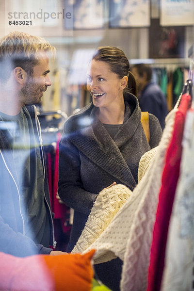 Glückliche Freunde beim Einkaufen von Pullovern im Bekleidungsgeschäft