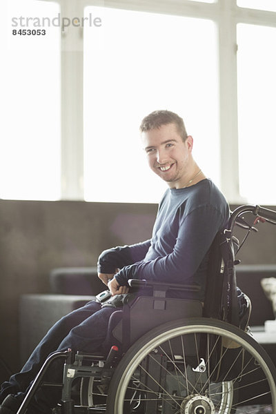 Porträt eines glücklichen behinderten Geschäftsmannes  der im Büro auf einem motorisierten Rollstuhl sitzt.