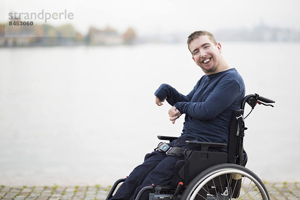 Porträt eines glücklichen Mannes mit zerebraler Lähmung im Rollstuhl am See