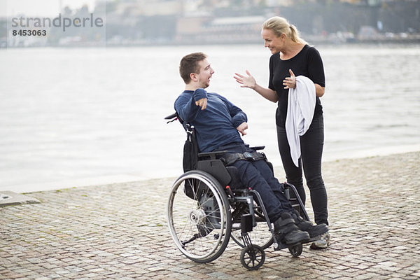 Behinderter Mann im Rollstuhl mit Hausmeisterin am See