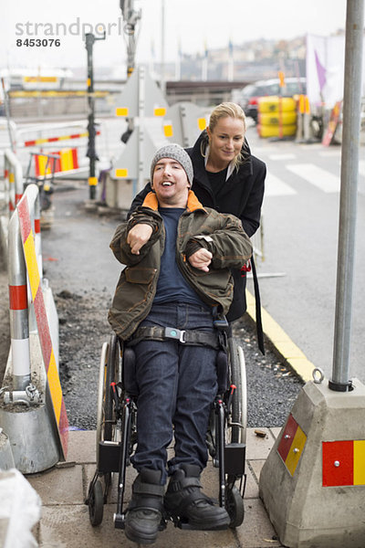 Hausmeister schiebt behinderten Mann im Rollstuhl ins Freie