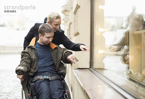 Behinderter Mann im Rollstuhl Witwe Einkaufen mit Hausmeister