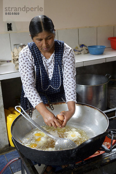 Schulküche  Köchin bereitet Spiegeleier zu  Carmen Pampa  Yungas  Departamento La Paz  Bolivien