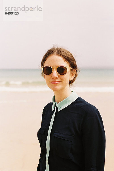 Eine Frau mit Sonnenbrille am Strand.