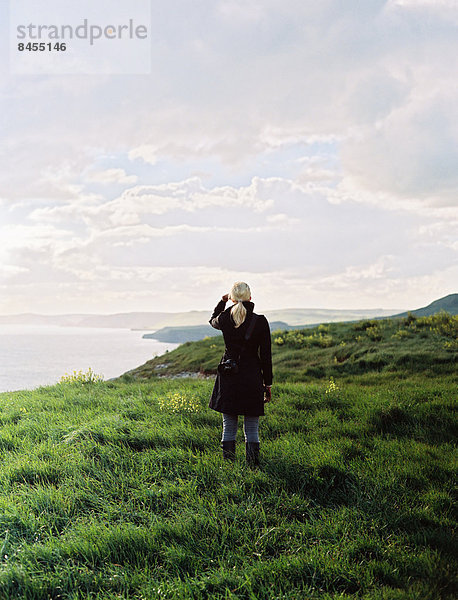 Eine Frau blickt entlang der Küstenlinie  Buchten und Klippen.
