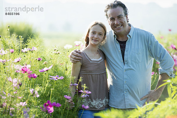 Sommer auf einem Biobauernhof. Ein Mann und ein Mädchen in einem Blumenfeld.