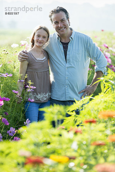 Sommer auf einem Biobauernhof. Ein Mann und ein Mädchen in einem Blumenfeld.