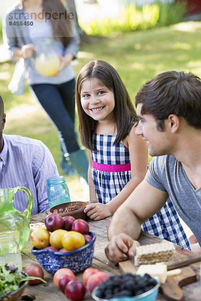 Erwachsene und Kinder um einen Tisch bei einer Party in einem Garten.