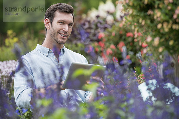 Eine Bio-Blumenpflanzengärtnerei. Ein Mann arbeitet mit einem digitalen Tablett.