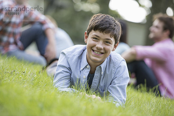 Ein Junge sitzt auf dem Rasen  bei einem Sommerfest.