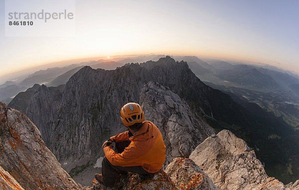 Bergsteiger sitz auf dem Gipfel des Ellmauer Halt bei Sonnenaufgang  Ellmau  Wilder Kaiser  Nordtirol  Österreich