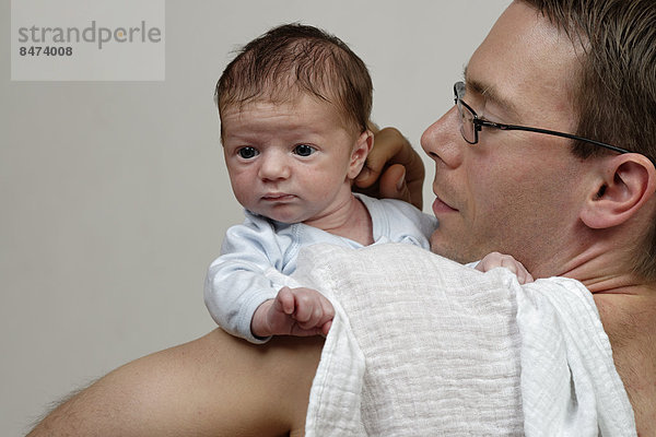 Drei Wochen alter Säugling  Junge wird von seinem Vater über der Schulter gehalten  mit Spucktuch