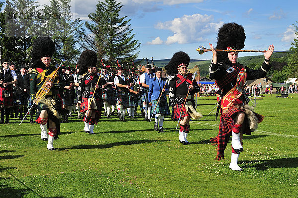 Pipe Band angeführt von mehreren Pipe Majors auf dem Sportplatz bei den Highland Games  Dufftown  Moray  Highlands  Schottland  Großbritannien