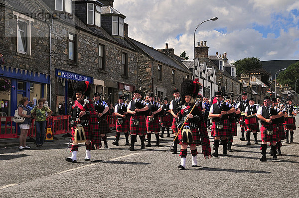 Die Pipe Band  angeführt vom Pipe Major  zieht im Gleichschritt durch die Ortschaft  Dufftown  Moray  Highlands  Schottland  Großbritannien