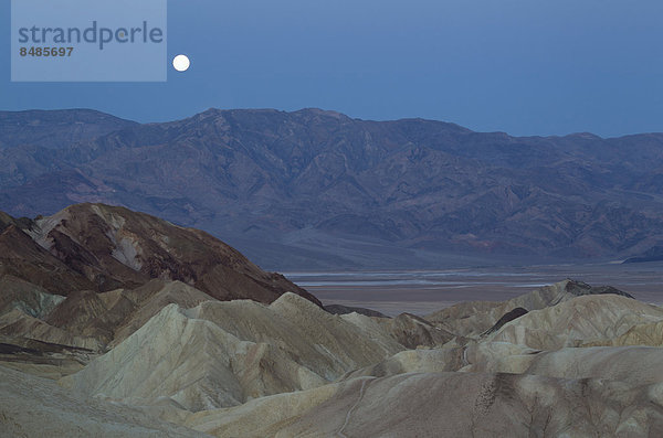 Vollmond ¸ber der Bergkette Panamint Range und dem Death Valley in der Morgend‰mmerung  vom Zabriskie Point  vorne Erosionsstrukten im Gestein  Badlands von Gower Gulch  Death-Valley-Nationalpark  Kalifornien  USA
