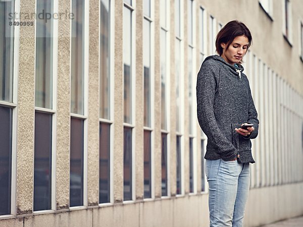 Junge Frau telefoniert sitzend vor beigem Sofa  Nahaufnahme