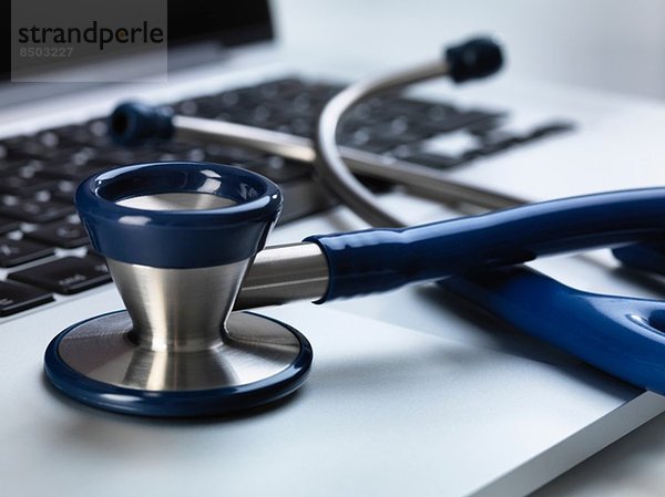 Stethoskop auf dem Laptop sitzend  das die Online-Gesundheitsfürsorge und den Arzttisch illustriert
