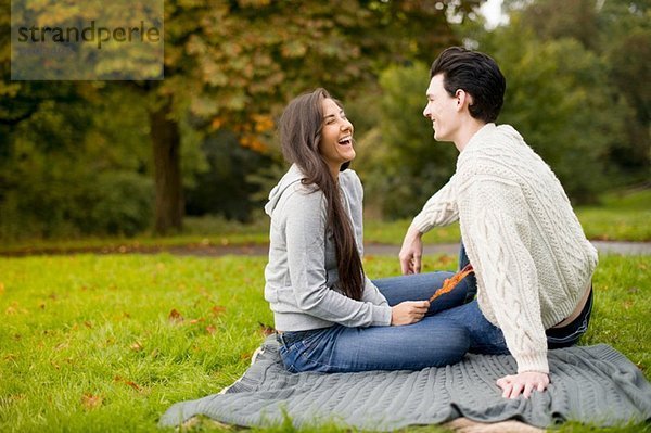 Junges Paar auf Decke im Park  lachend