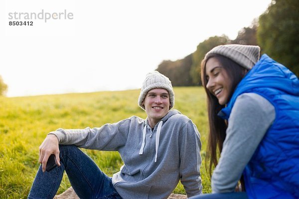 Junges Paar auf Gras sitzend lachend