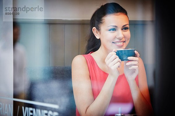 Junge Frau sitzend im Café mit heißem Getränk