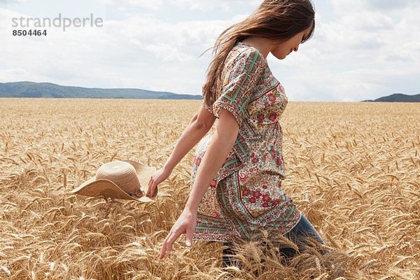 Mittlere erwachsene Frau  die durch das Weizenfeld läuft.